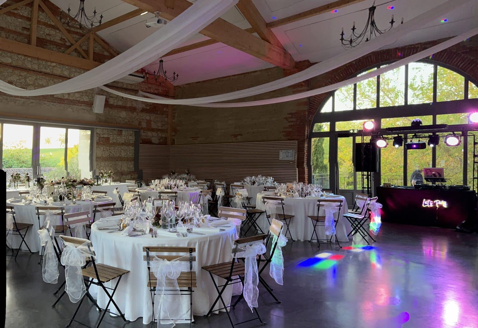 Salle de réception décorée pour un mariage avec tables rondes et animation DJ